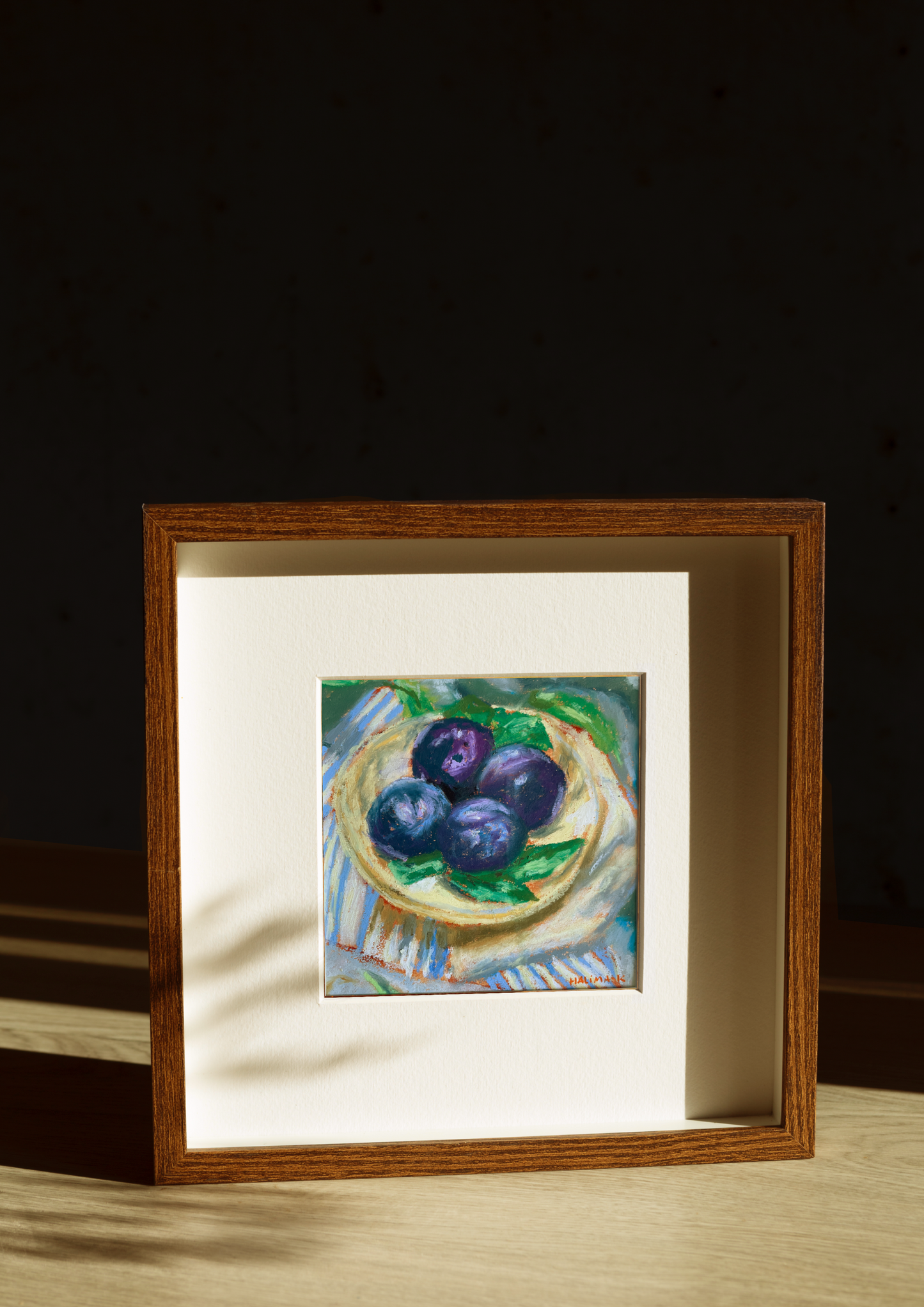 Framed artwork of a still life with plums in golden hour light