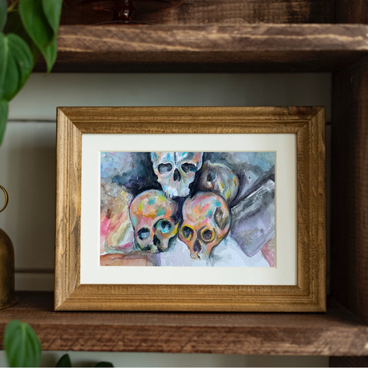 Framed artwork of colorful skulls on a wooden shelf.