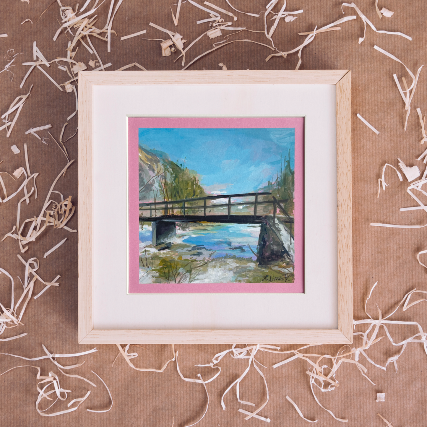 Framed painting of a bridge over water on a brown textured background