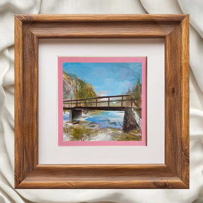 Painting of a bridge and stream near Lake Bohinj. Brown wooden frame, fabric backgorund. artist halima khanum. 