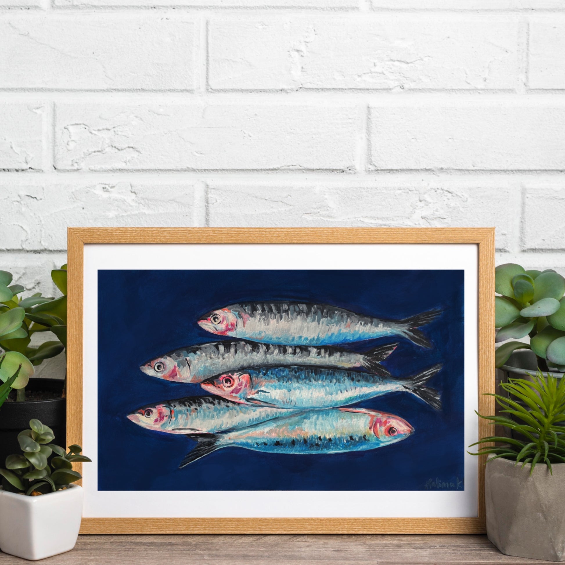 Framed original painting of food art - fish on a blue background against a white brick wall.
