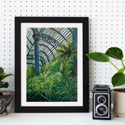 Framed artwork of a lush greenhouse garden scene on a white wall with a vintage camera and planters.