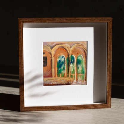 Framed mini painting of architectural scene on a wooden surface with dark background